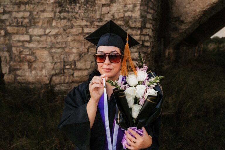Graduation photo of woman in cap and gown standing in desert at golden hour in Southeast New Mexico